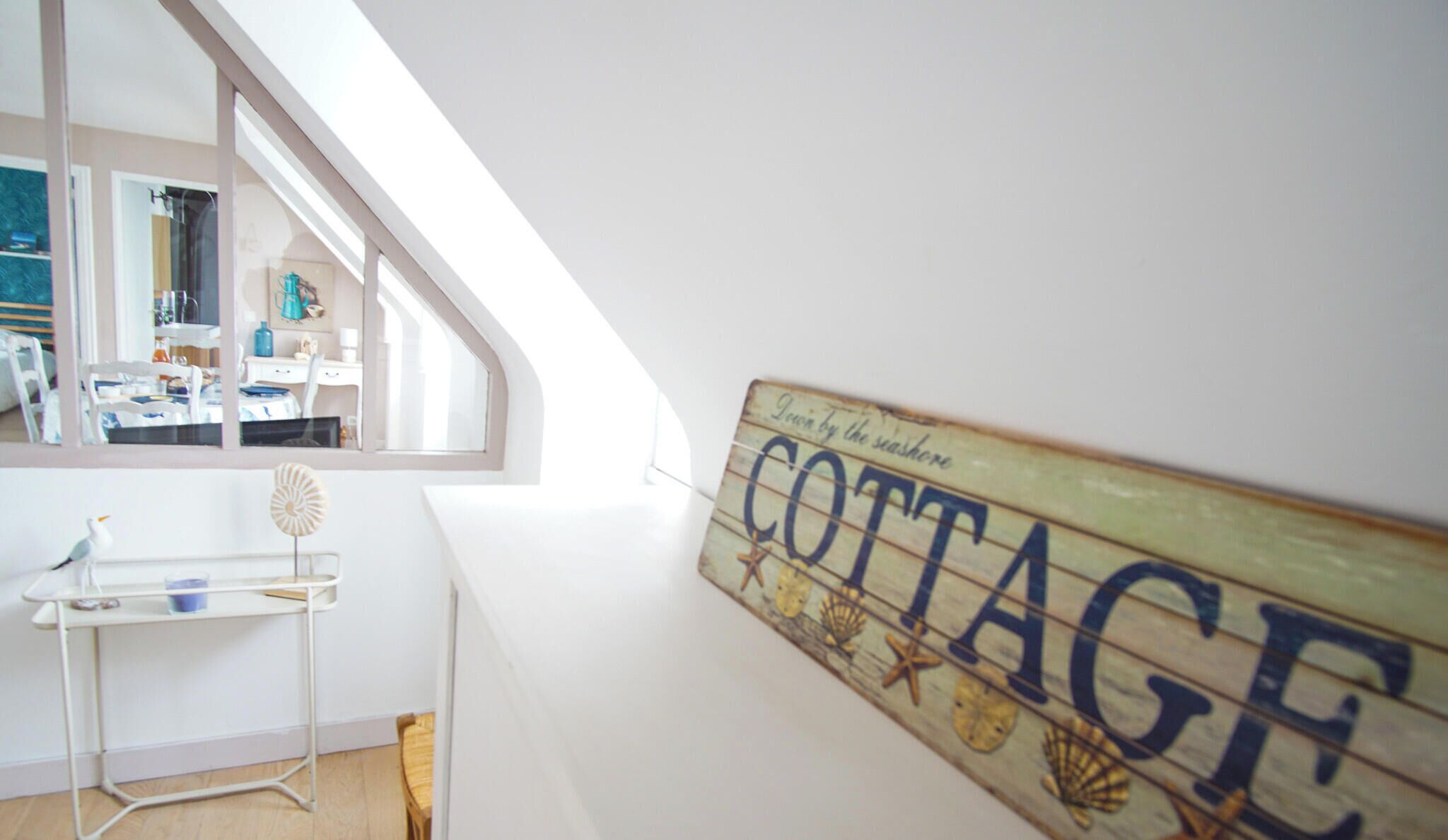 Ein Zimmer mit Hochbett, einem kleinen Tisch und einem an der Wand befestigten Schild mit der Aufschrift 'COTTAGE'.