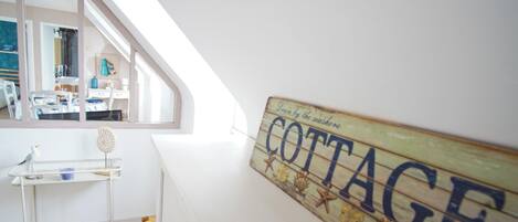 Ein Zimmer mit Hochbett, einem kleinen Tisch und einem an der Wand befestigten Schild mit der Aufschrift 'COTTAGE'.