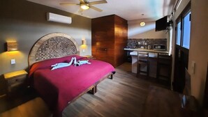 Ein Schlafzimmer mit Bett, Deckenventilator, eingebautem Kamin und einer Küchenzeile.