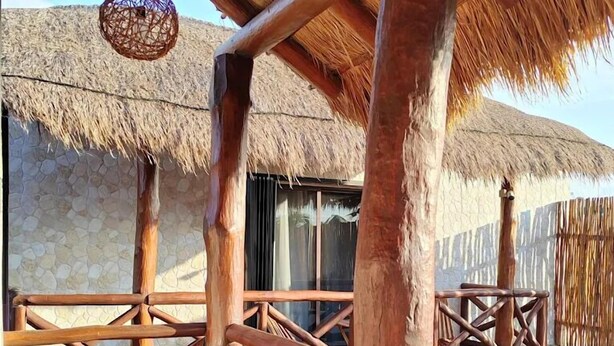 Eine Holzdar Terrasse mit Strohdächern, Holzgeländern und einer hängenden Leuchte.