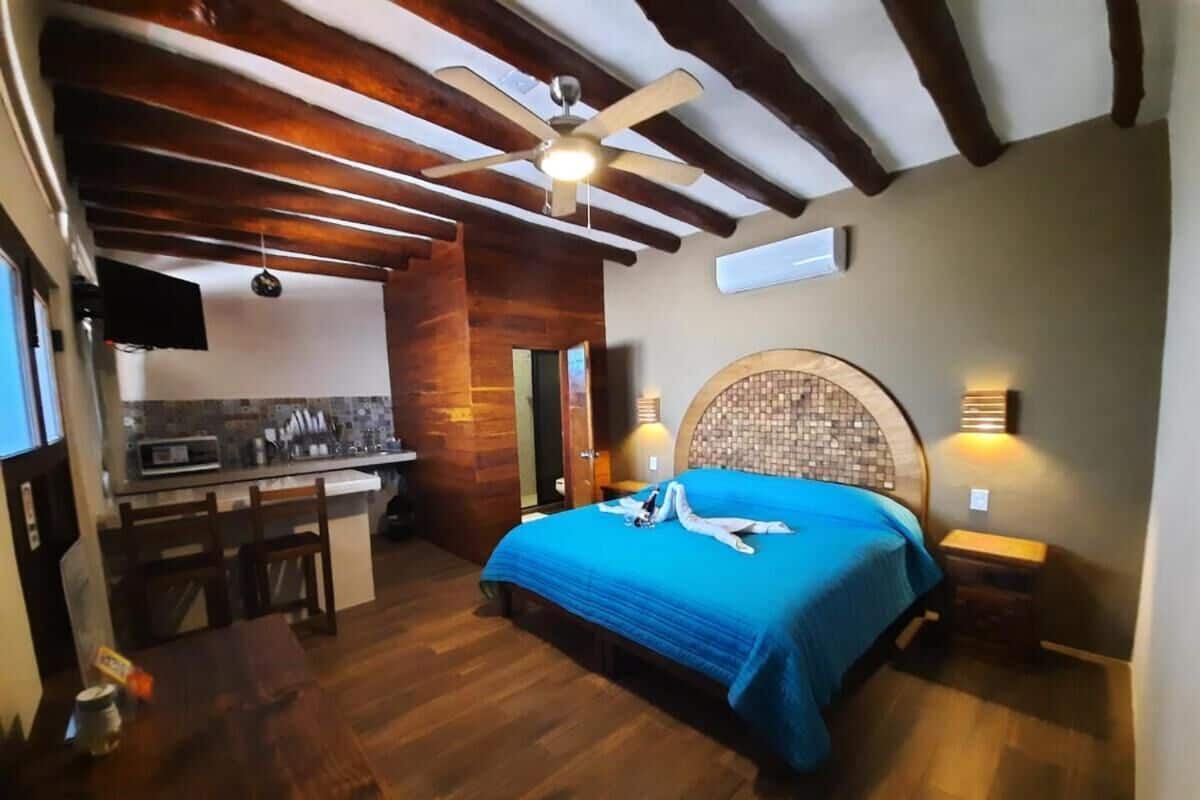 Egy hálószoba, amelyben található egy ágy, egy kis asztal, egy szék, egy mennyezeti ventilátor, egy kör alakú ágyvég, valamint egy konyhasarok mikrohullámú sütővel.