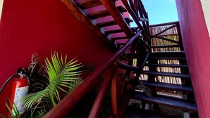 Eine Holztreppe mit roter Wand und einem Feuerlöscher links.
