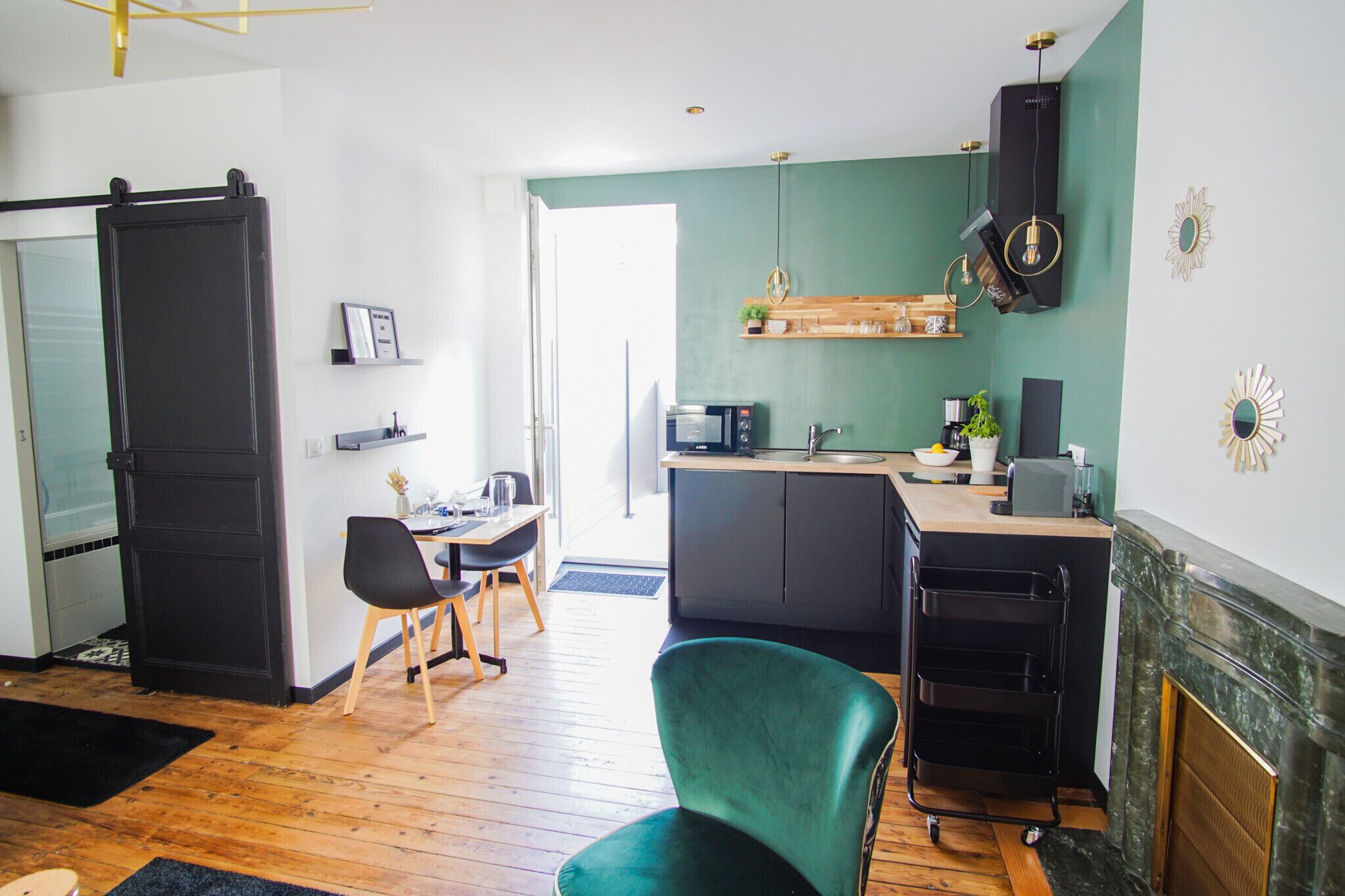 A modern kitchen with a dining area, a black refrigerator, a microwave, and a fireplace.