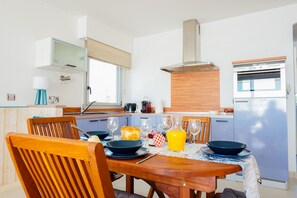 Une cuisine moderne avec une table à manger pour deux, un four encastré et une fenêtre au-dessus de l’évier.