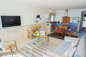 Un salon moderne équipé d’un téléviseur, de meubles en bois, d’un coin repas et d’une cuisine.