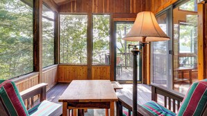 Eine Holzdielen-Terrasse mit Tisch, Stühlen, einer Lampe und einem Hirschgeweih an der Wand.