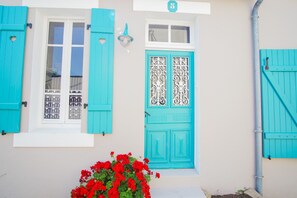 A building with turquoise shutters, a decorative door, and a number '5' sign.