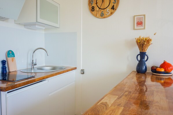 Une cuisine dotée d’un plan de travail en bois, d’un évier en acier inoxydable et d’une horloge murale.