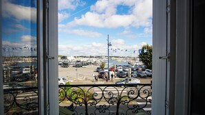 A view of a marina with boats, a parking lot, and a clear sky. - -BOSCO- ÉLÉGANT T3 AVEC BALCON ET VUE SUR LE PORT (Concarneau)