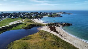 Luchtbeeld van een kustdorpje met huizen, een strand en een klein waterlichaam.