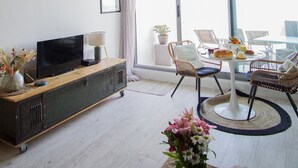 Un salon moderne comprenant un téléviseur, un canapé, une table à manger et des chaises.
