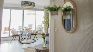 Une pièce spacieuse dotée d’une grande fenêtre, de meubles en osier, d’un luminaire suspendu et de jardinières fixées au mur.