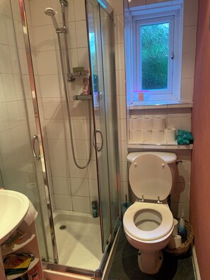 A bathroom with a glass-enclosed shower, a toilet, and a window above the sink. - Edinburgh City Escape - Large 1 Bedroom Apartment (Edinburgh)