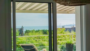 Un balcón con vista al mar, una silla y una planta en maceta.
