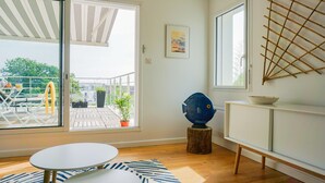Una habitación con puerta corrediza de vidrio que da a una terraza exterior, una mesa redonda, un objeto decorativo azul y un armario blanco.