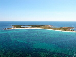 Vue aérienne d’une zone côtière avec des eaux turquoise limpides, des plages de sable et de petites îles.
