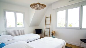 Een slaapkamer met twee bedden, een ladder, een stoel en een hanglamp.