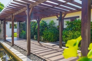 A covered outdoor area with a pool, wooden pergola, and lush greenery. - Villa Cantik Pandawa By Fays Hospitality (Bali)