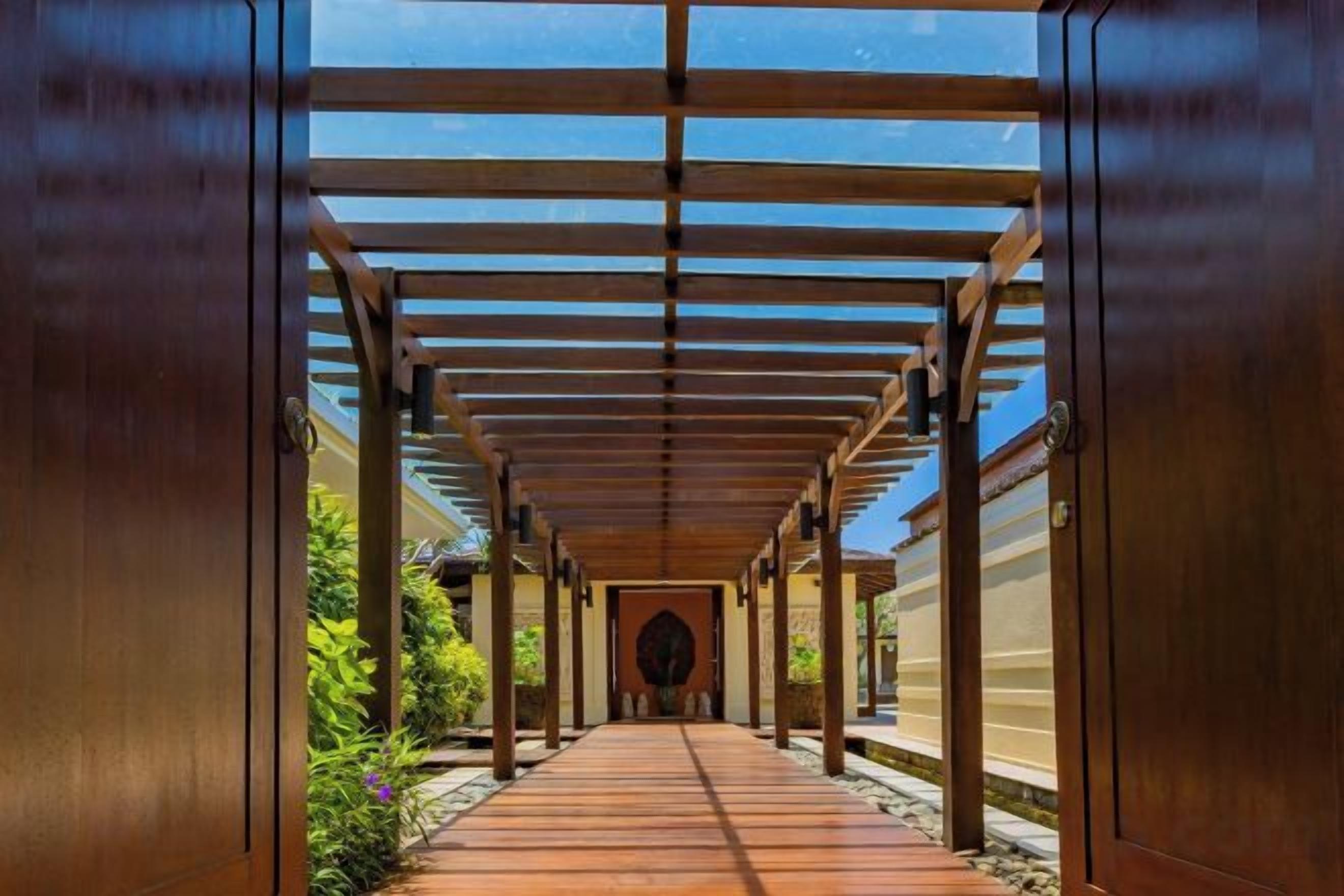A covered walkway with a wooden floor and metal railings, leading to a circular opening.