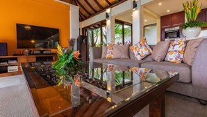 A modern living room with a sofa, a glass coffee table, and a television. - Villa Cantik Pandawa By Fays Hospitality (Bali)
