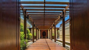 A wooden covered walkway leading to a building entrance. - Villa Cantik Pandawa By Fays Hospitality (Bali)