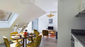 Eine moderne Küche mit Essbereich, gekennzeichnet durch hohe Decken, ein Oberlicht und zeitgemäße Möbel.