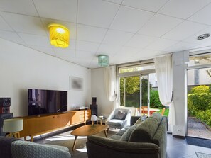 Een moderne woonkamer met een flatscreen televisie, een houten entertainmentkast en comfortabele zitplaatsen.