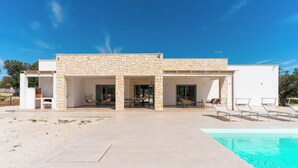 A modern house with a stone facade, a swimming pool, and outdoor seating.