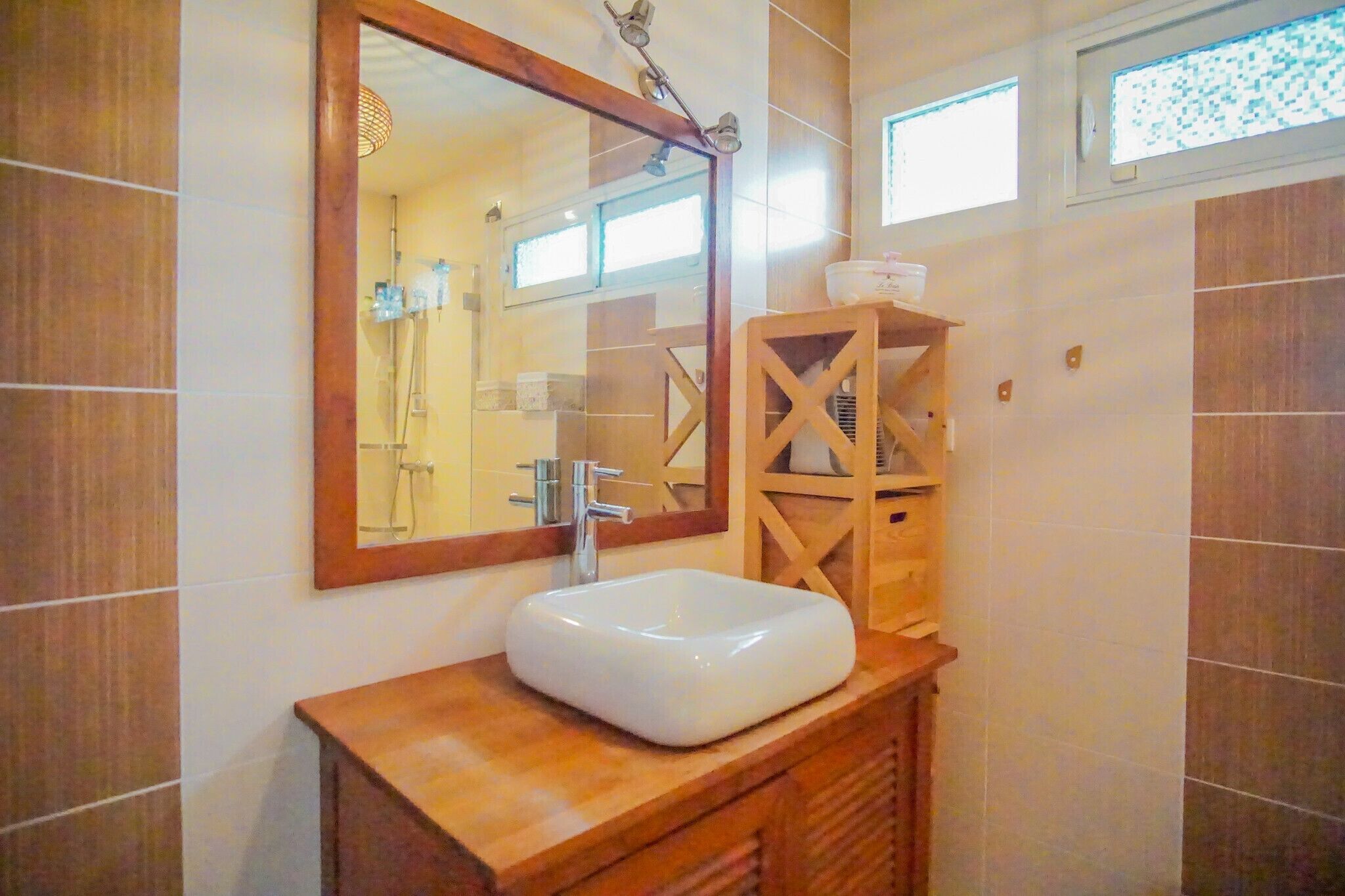 Une salle de bain avec un meuble-lavabo en bois, un lavabo blanc et un miroir.