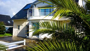 A modern house with a balcony, large windows, and a solar panel on the roof.