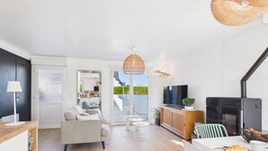 Una sala moderna con sofá, televisión, mesa de comedor y chimenea.