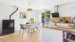 Una cocina moderna con estufa integrada, comedor con sillas y vista a zonas verdes.