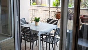 A balcony with a table and chairs, a potted plant, and a view of a building.