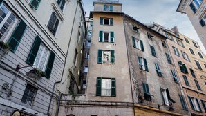 A multi-story building with a mix of architectural styles, featuring arched windows and a central balcony. - Art near Lomellini Street by Wonderful Italy (Genoa)
