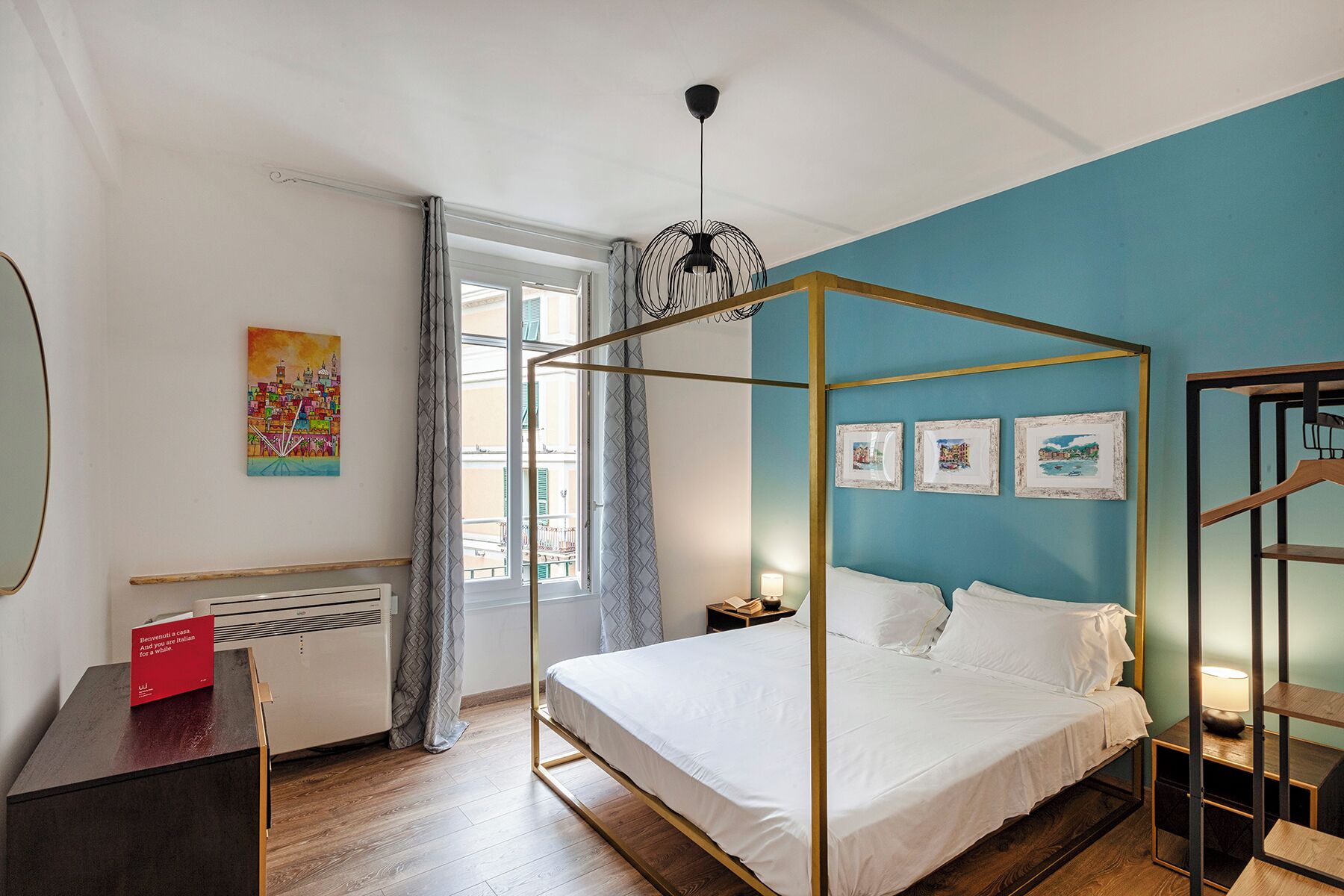 Ein Schlafzimmer mit einem Himmelbett, einem Schreibtisch mit einem roten Schild, einem Heizkörper und einem Fenster mit Vorhängen.