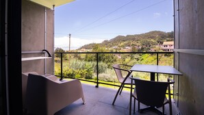 Un balcon avec une table et des chaises, donnant sur une colline parsemée de maisons.
