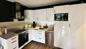 Una cocina moderna con armarios blancos, electrodomésticos de acero inoxidable y suelo de madera.