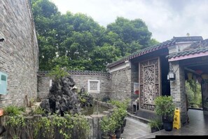 A courtyard with traditional architecture, including a stone wall, a decorative wooden screen, and a small rock garden. - Huangyao Bandao Hotel (Zhaoping)