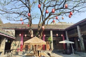 Un patio tradicional con un árbol, faroles y una estructura de techo de paja.