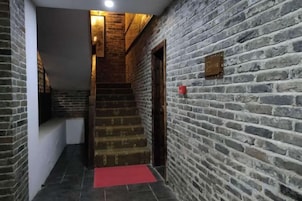 Una escalera con alfombra roja que lleva a una puerta, rodeada de muros de ladrillo.