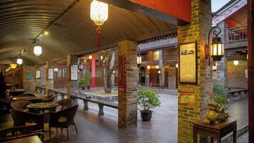 An indoor courtyard with stone pillars, lanterns, and traditional furniture.