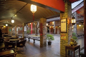 Un patio interior con pilares de piedra, faroles y mobiliario tradicional.