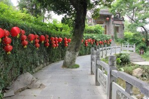 A pathway lined with red lanterns, a stone fence, and a traditional building in the background. - Huangyao Bandao Hotel (Zhaoping)