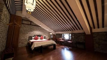 Un dormitorio con cama, una silla, una mesa y una chimenea.