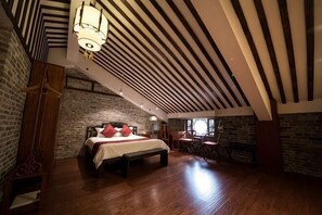 A bedroom with a bed, a chair, a table, and a fireplace. - Huangyao Bandao Hotel (Zhaoping)