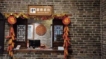 A service desk with a sign, a computer, and traditional decorations.