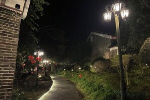 A pathway flanked by brick walls and greenery, with street lamps and red lanterns. - Huangyao Bandao Hotel (Zhaoping)