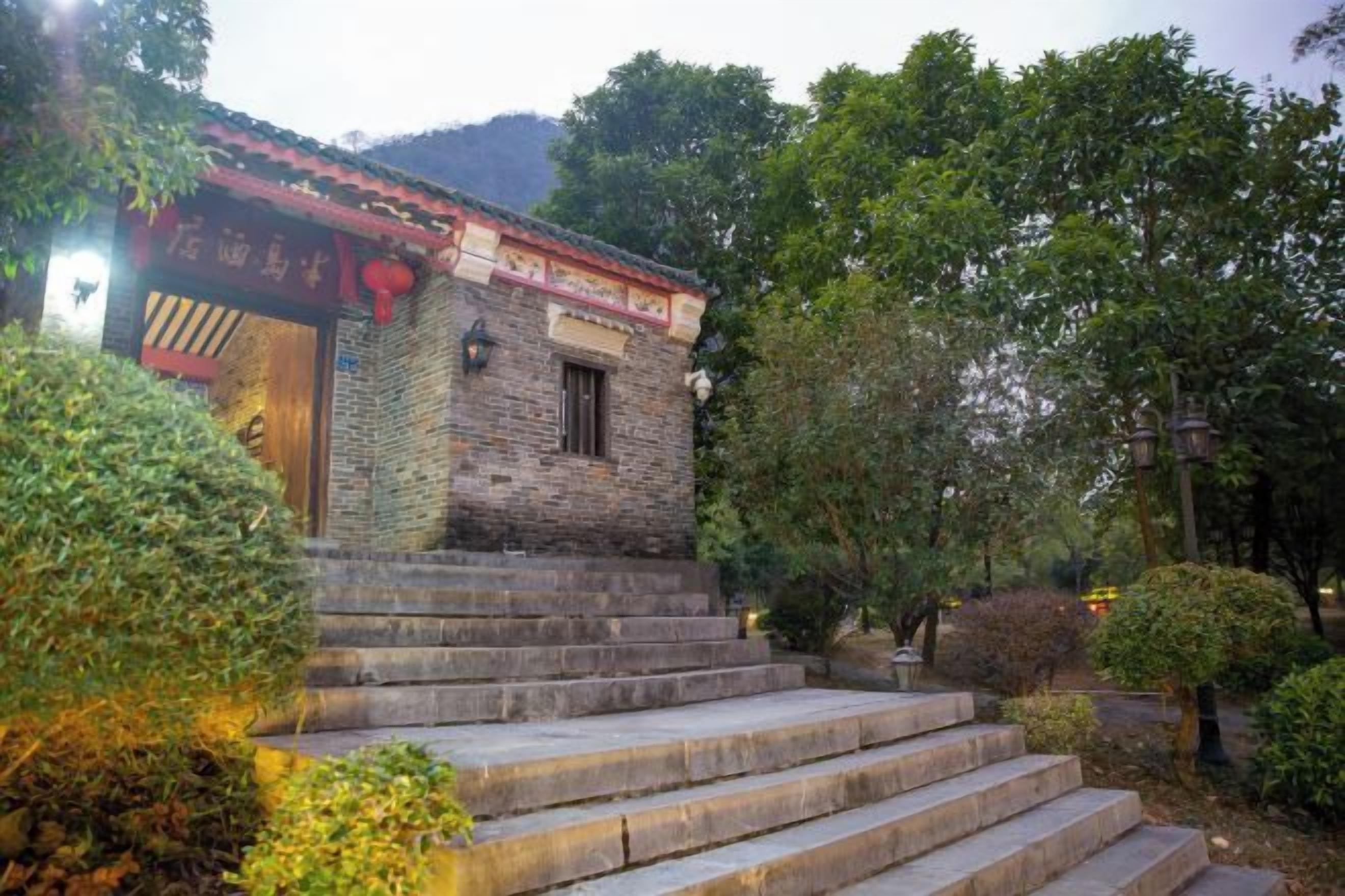 Un bâtiment traditionnel avec des marches en pierre menant à une porte, le tout entouré de verdure.