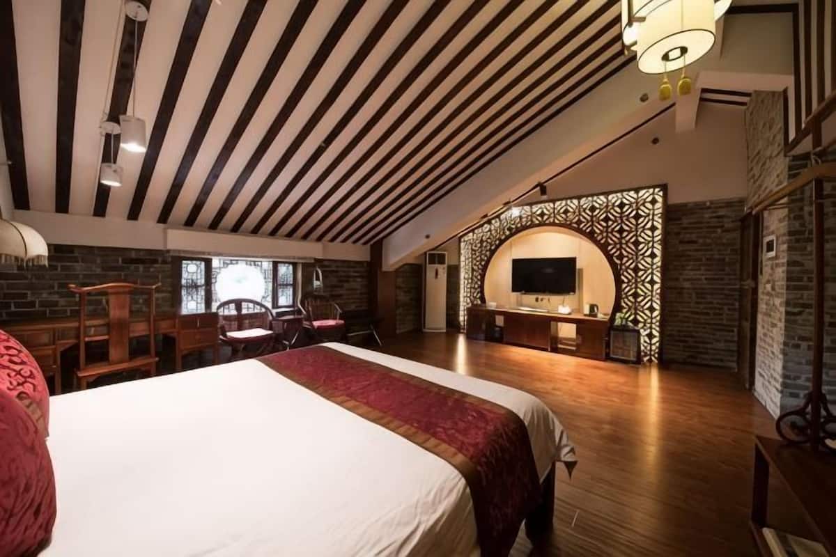 Una habitación amplia con una cama grande, televisión y un área de descanso con sillas.