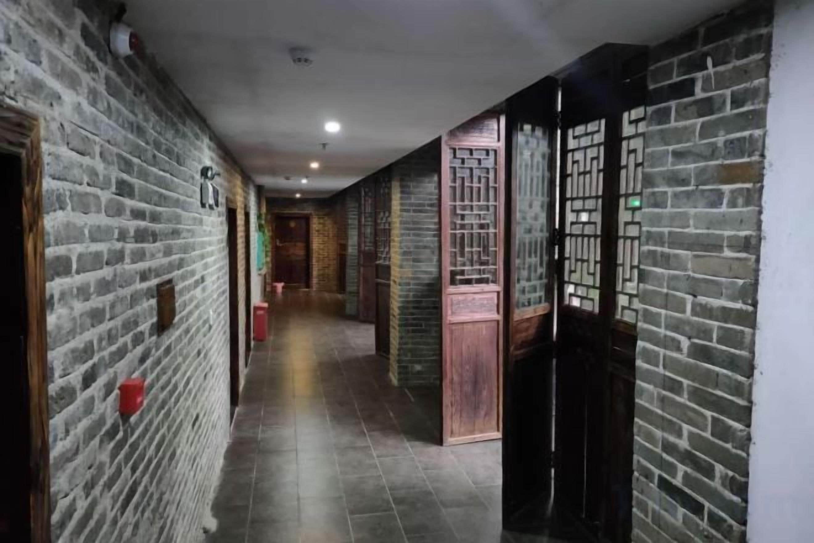 Un pasillo con paredes de ladrillo, puertas de madera y suelo de baldosas.